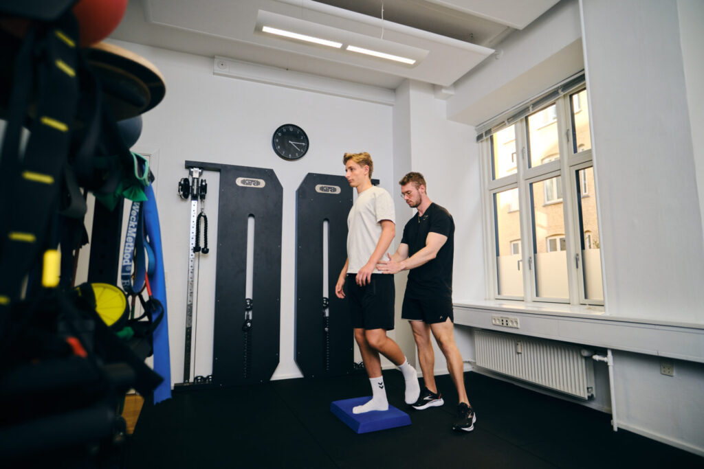 Fysioterapeut hjælper klient med balanceøvelse for at forbedre stabilitet og reducere smerter