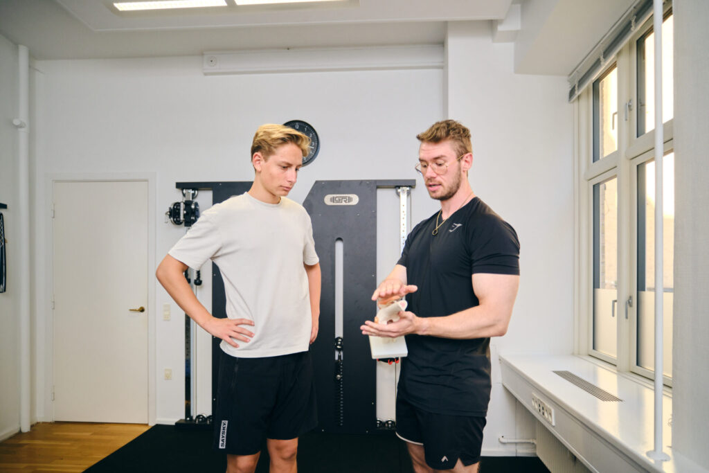 Fysioterapeut forklarer kroppen og smerter til klient i behandling