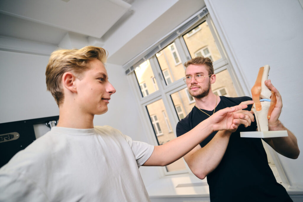 Fysioterapeut fra Fysio360 i København forklarer patienten knæets anatomi med model